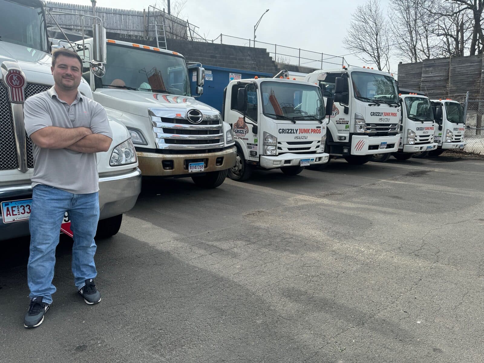 Justin Hubbard standing in front of the Grizzly Junk Pros truck fleet